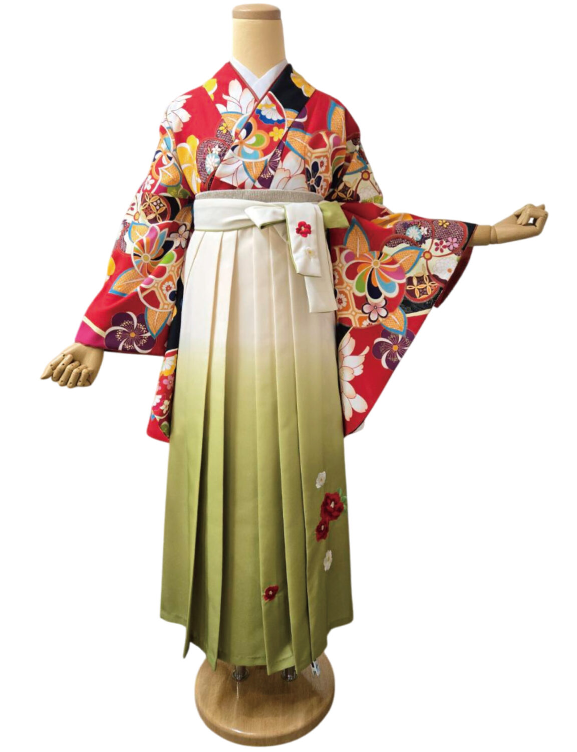 赤地に花柄と伝統文様が施された着物と椿刺繍入りの袴の組み合わせ