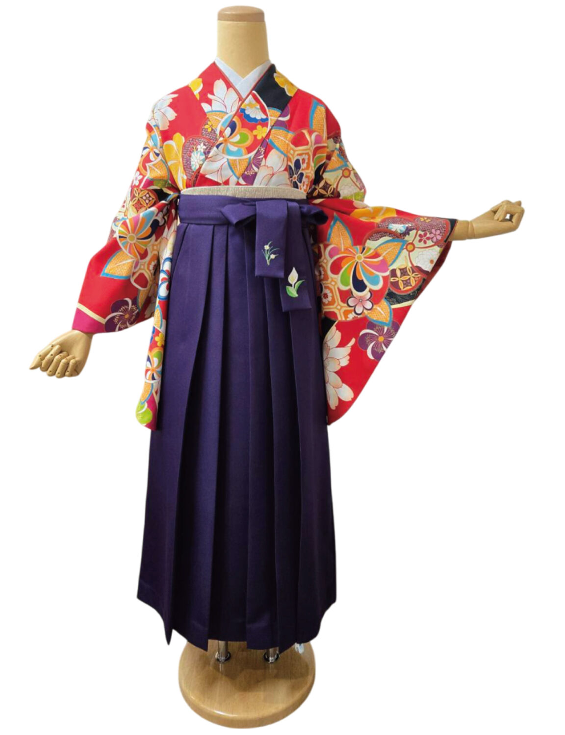 赤地に花柄と伝統文様が施された着物と紫の袴の組み合わせ