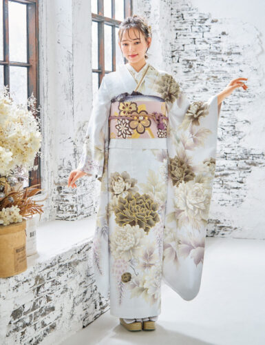 ほのかにシルバーがかった白い振袖が叶える、清楚な立ち姿。見頃を迎えた牡丹や藤はいきいきと写実的な花姿で、色味を抑えた意匠が際立ちます。