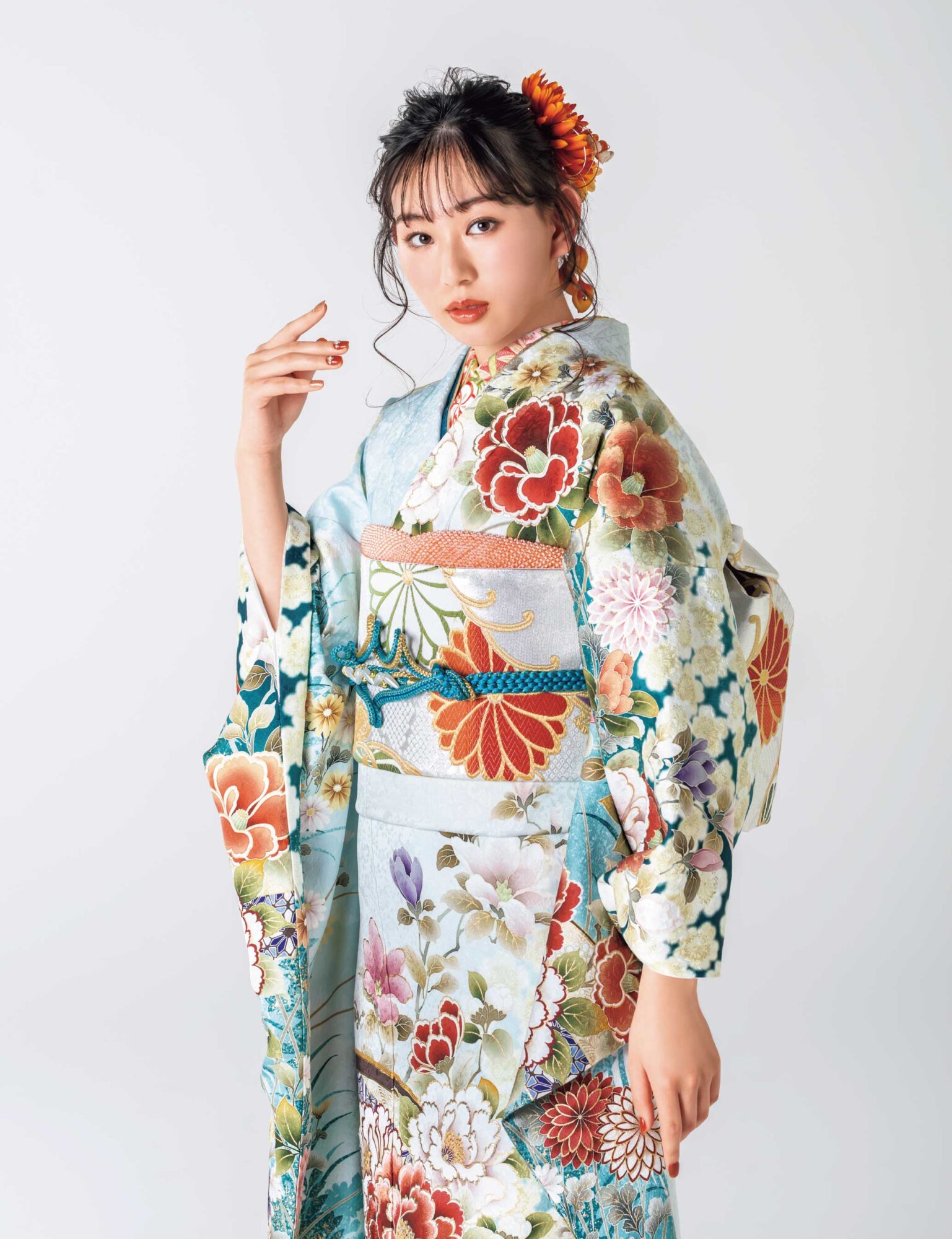 水色から深青への振袖に牡丹や菊をあしらい、金彩と青の帯締を合わせた女性の立ち姿