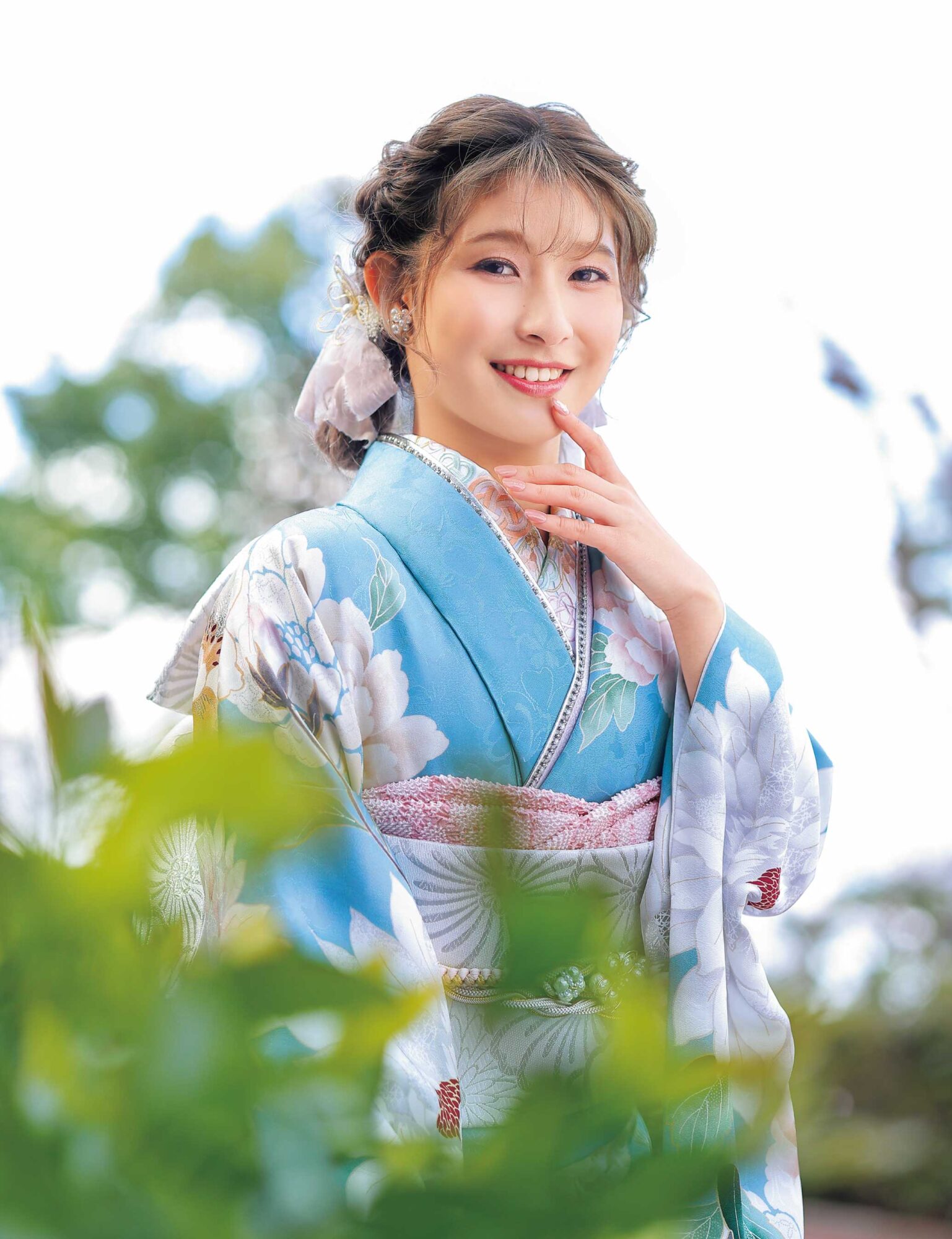 水色の振袖に白牡丹と淡い花々をあしらい、銀灰色の帯と帯締を合わせた女性の立ち姿
