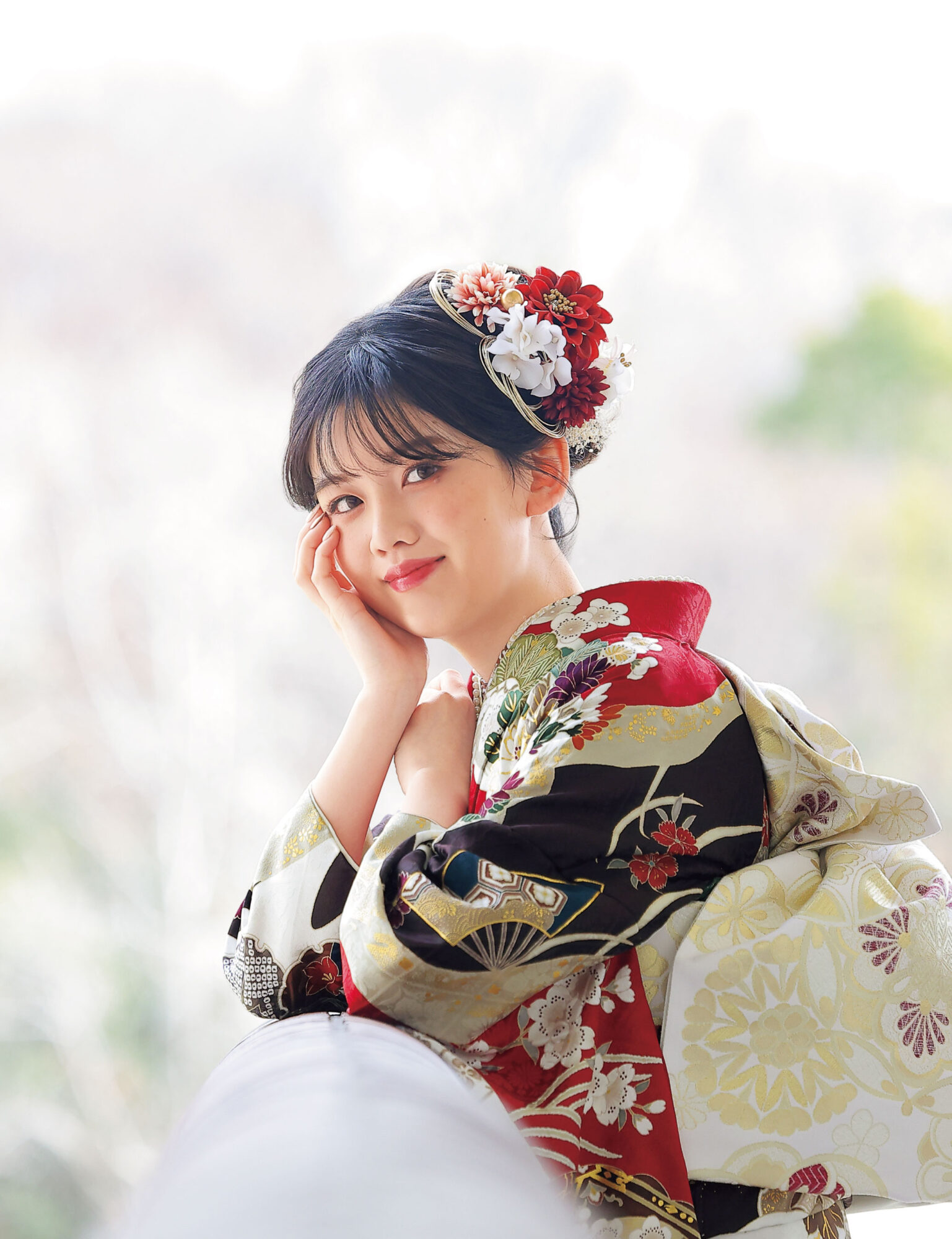 深紅の振袖に牡丹と菊、金彩と幾何文様をあしらい、赤の帯締を合わせた女性の立ち姿