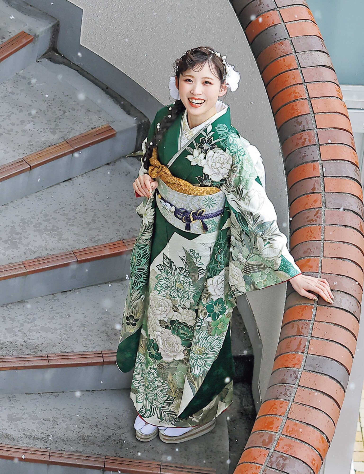 深緑の振袖に白牡丹と菊の花模様をあしらい、金の帯と濃紺の帯締を合わせた女性の立ち姿