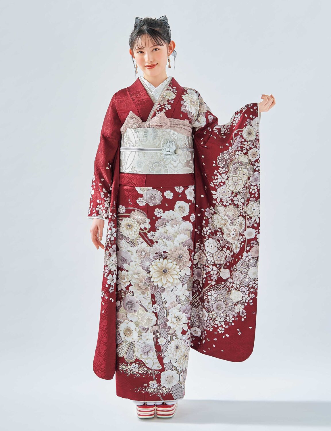 深紅の菊文様振袖を着た女性。銀の帯締がアクセントになった華やかな装い。