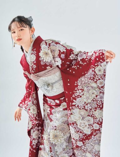 深紅の菊文様振袖を着た女性。銀の帯締がアクセントになった華やかな装い。