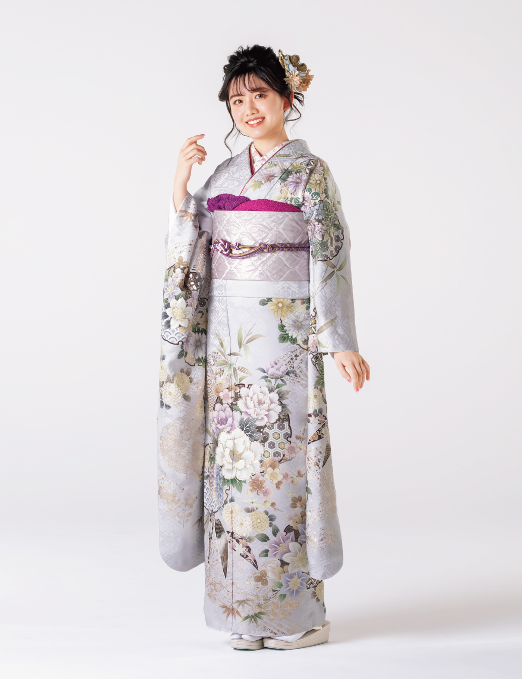 銀鼠色の振袖に白と紫の花々をあしらい、紫の帯締を合わせた女性の立ち姿