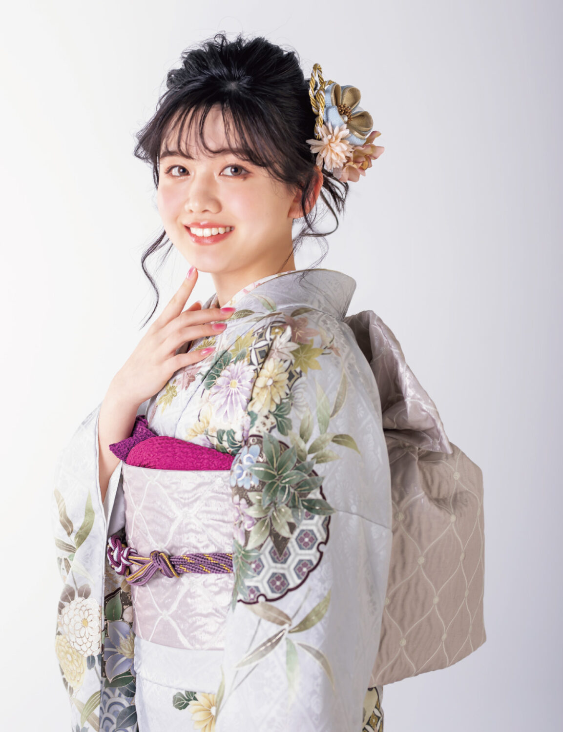 銀鼠色の振袖に白と紫の花々をあしらい、紫の帯締を合わせた女性の立ち姿