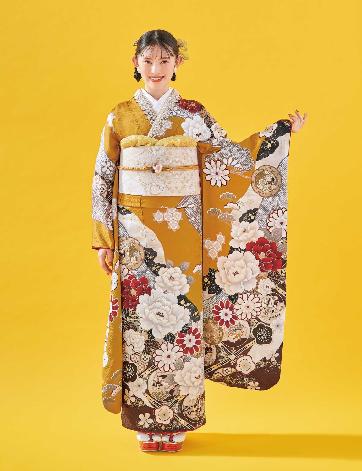 白地に紅・金の花柄があしらわれた振袖姿の女性。白と金の帯締がアクセント。