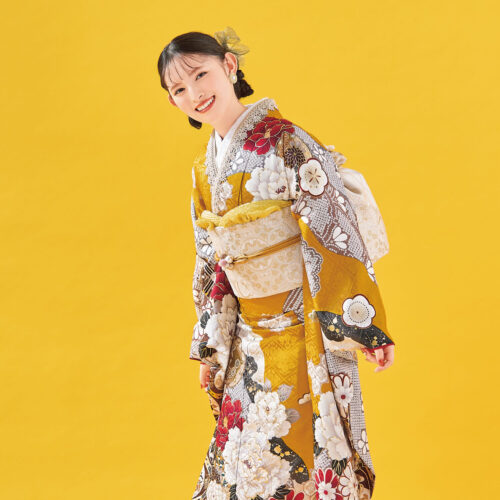 白地に紅・金の花柄があしらわれた振袖姿の女性。白と金の帯締がアクセント。