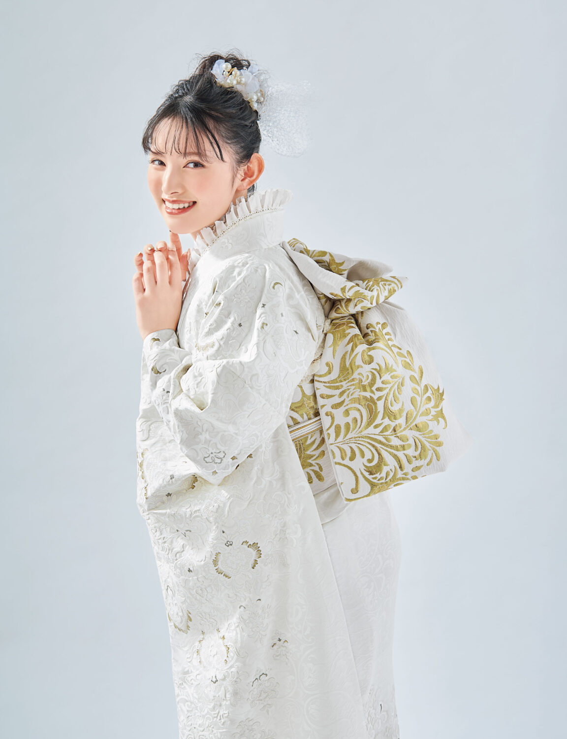 白地に金刺繍が施された振袖を着た女性。帯締が華やかさを添える格式高い装い。