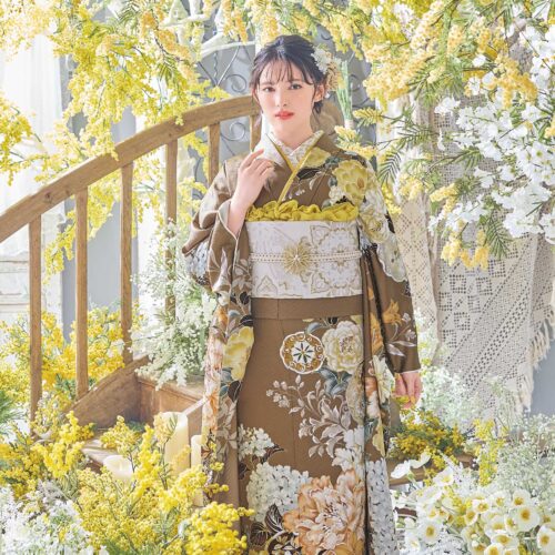 茶色地に花柄が咲く振袖姿の女性。金銀の帯締がアクセント。