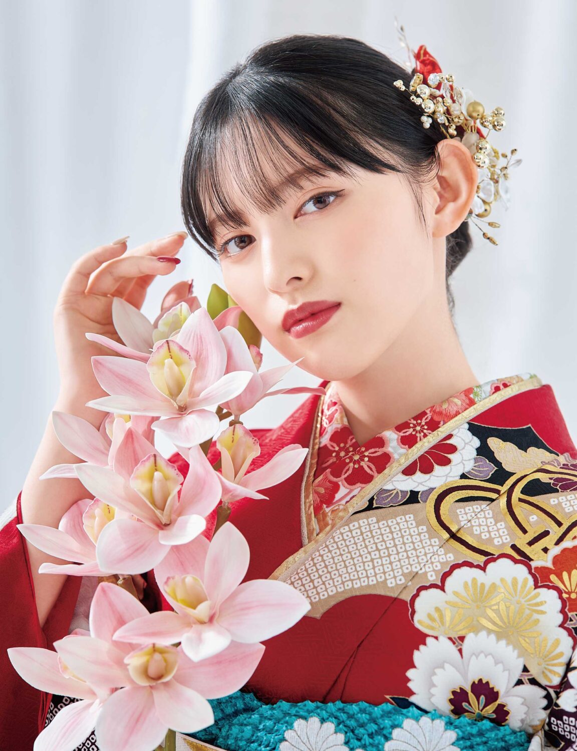 菊と梅の文様が施された白黒金の振袖を着た女性。青の帯締と花の髪飾りが印象的。