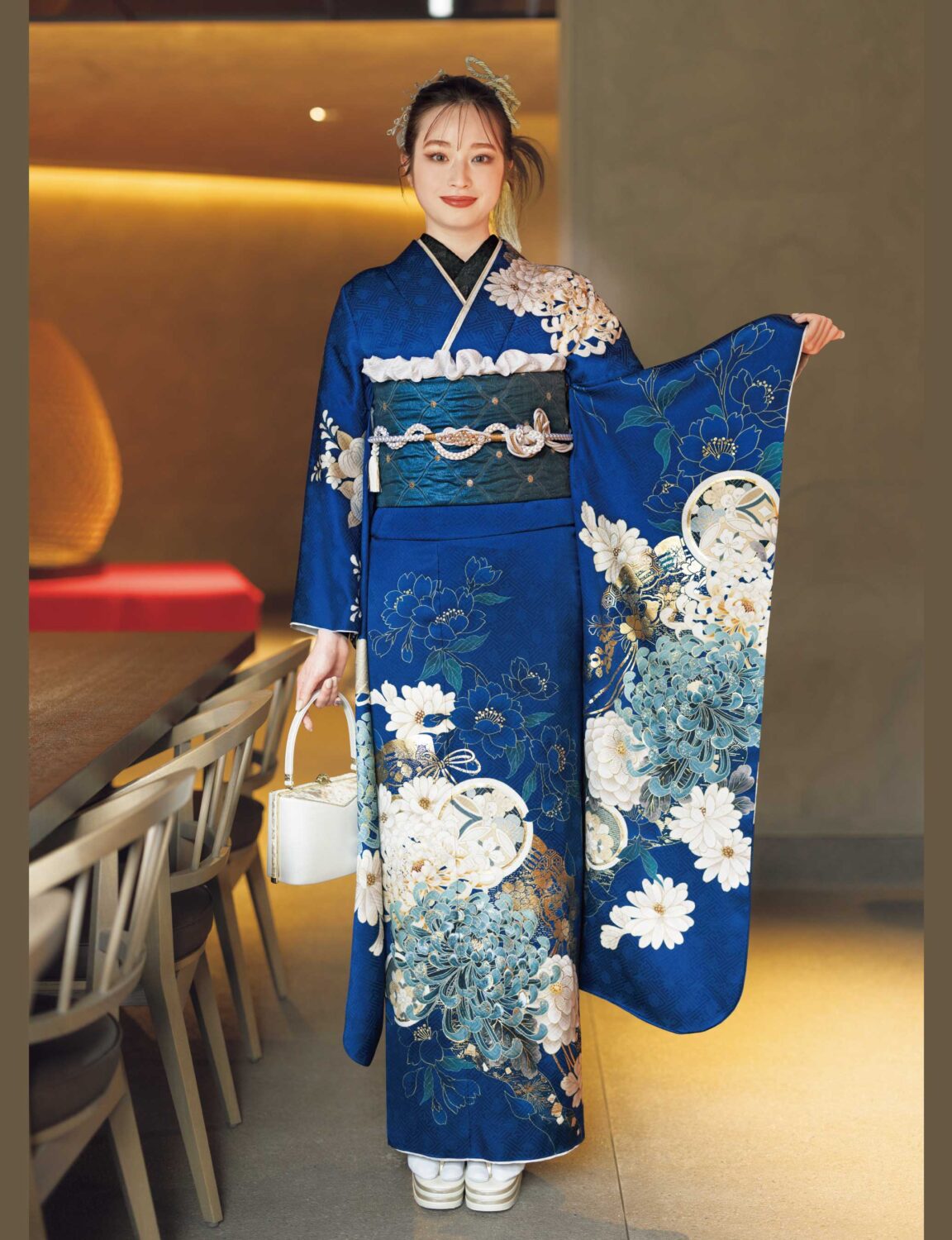 白金の花模様が美しい深藍の振袖を着た女性。気品ある帯締がアクセント。