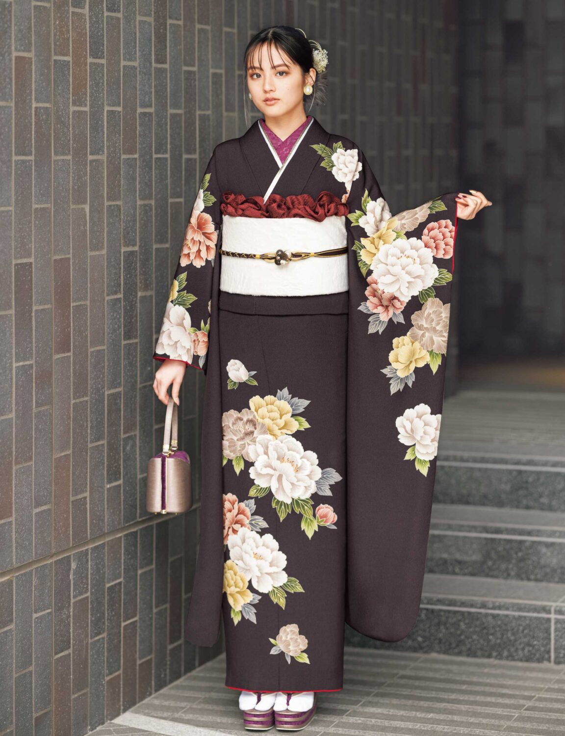 黒地に大輪の花が描かれた振袖を着た女性。白の帯締と小物が上品な印象を添えている。