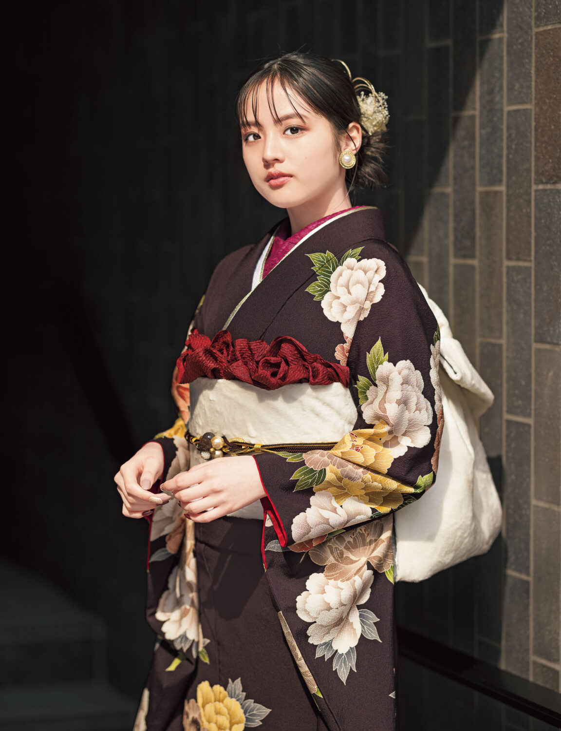 黒地に大輪の花が描かれた振袖を着た女性。白の帯締と小物が上品な印象を添えている。