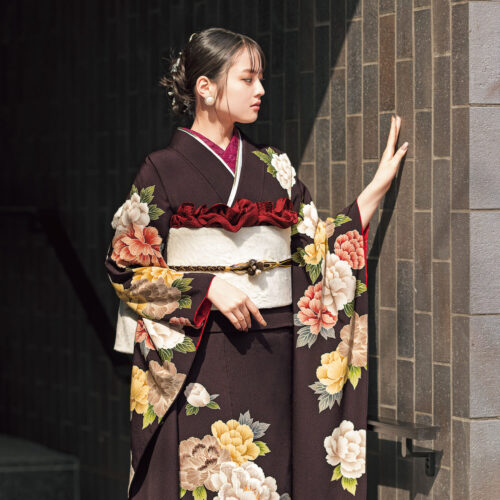 黒地に大輪の花が描かれた振袖を着た女性。白の帯締と小物が上品な印象を添えている。