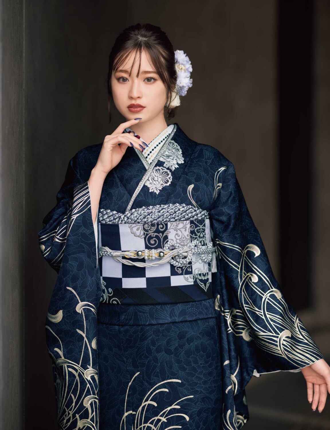 藍地に銀の菊模様が施された振袖姿の女性。帯締とバッグが調和し、優美な印象を与える装い。