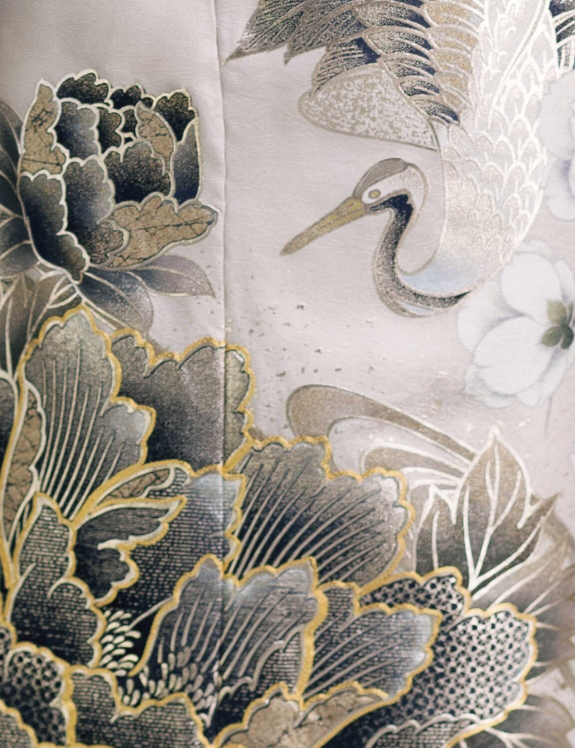 鶴と花模様の振袖を着た女性が、黒の帯締を合わせて優雅に袖を広げている姿