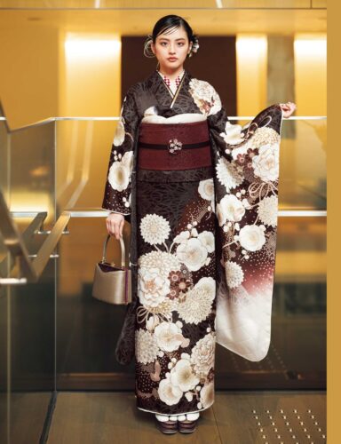 茶系に白花が咲く振袖姿の女性、深紅の帯締と花飾りが上品な印象を演出