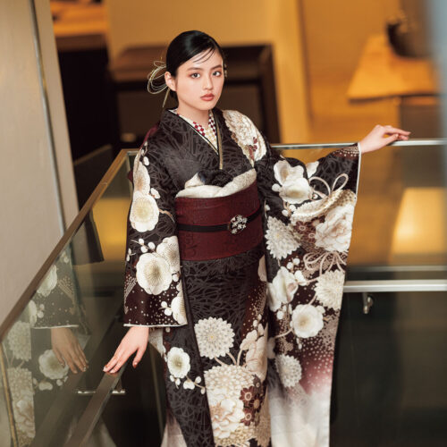 茶系に白花が咲く振袖姿の女性、深紅の帯締と花飾りが上品な印象を演出