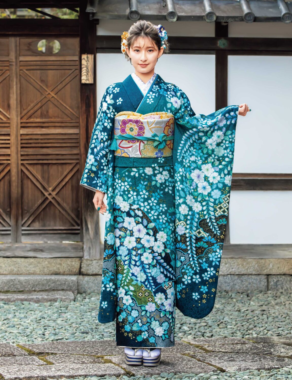 青緑の振袖に白花模様と帯締が映える、格式と華やぎを纏った女性の晴れ姿