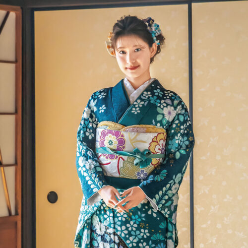 青緑の振袖に白花模様と帯締が映える、格式と華やぎを纏った女性の晴れ姿