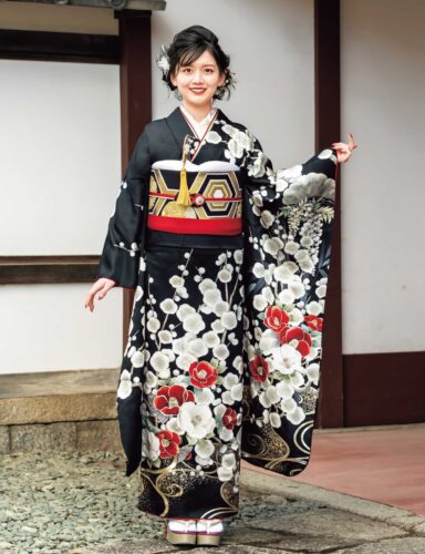 黒地に紅白の花柄が施された振袖を着た女性。赤の帯締と華やかな髪飾りが印象的。