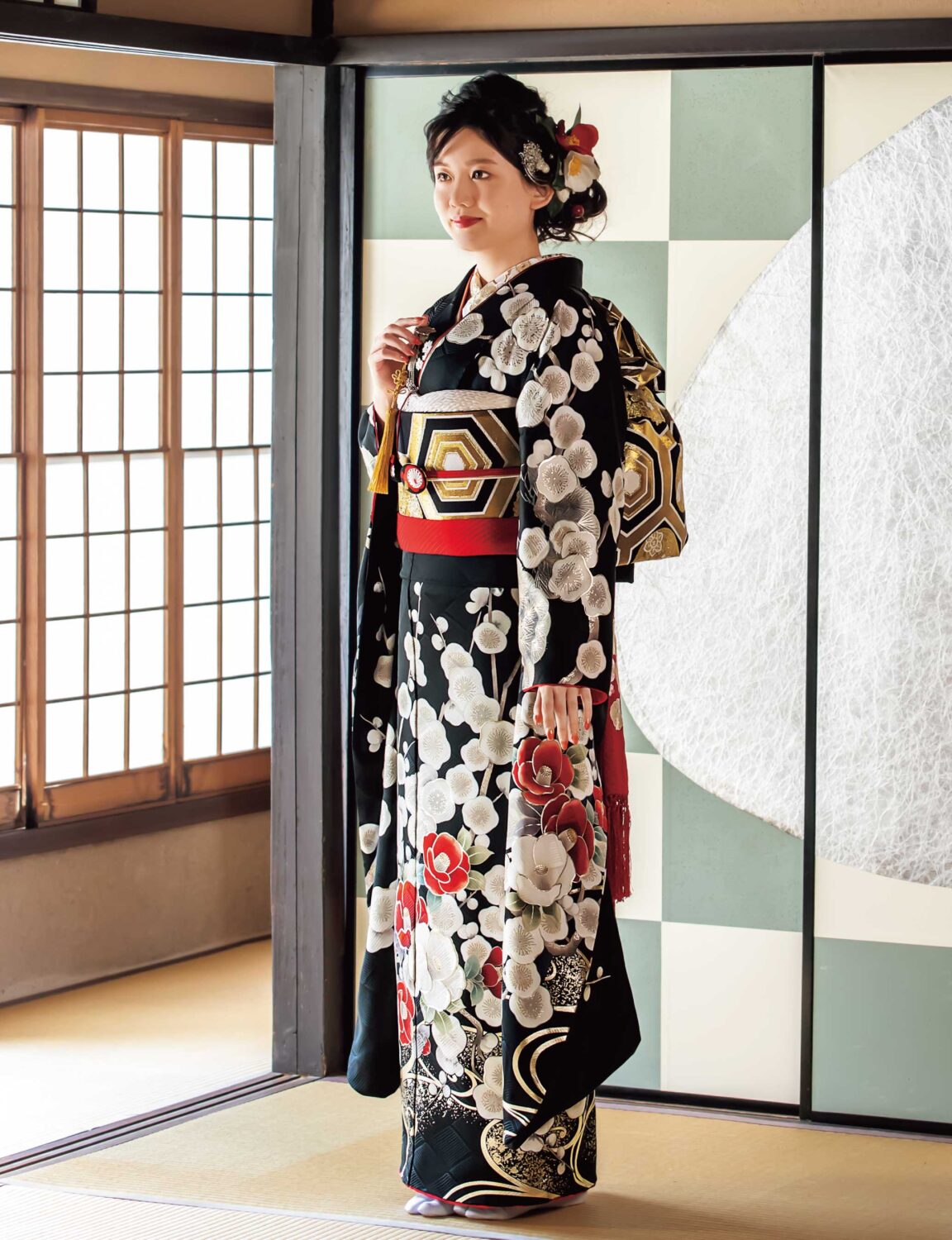 黒地に紅白の花柄が施された振袖を着た女性。赤の帯締と華やかな髪飾りが印象的。