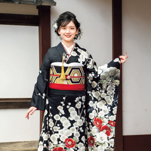 黒地に紅白の花柄が施された振袖を着た女性。赤の帯締と華やかな髪飾りが印象的。