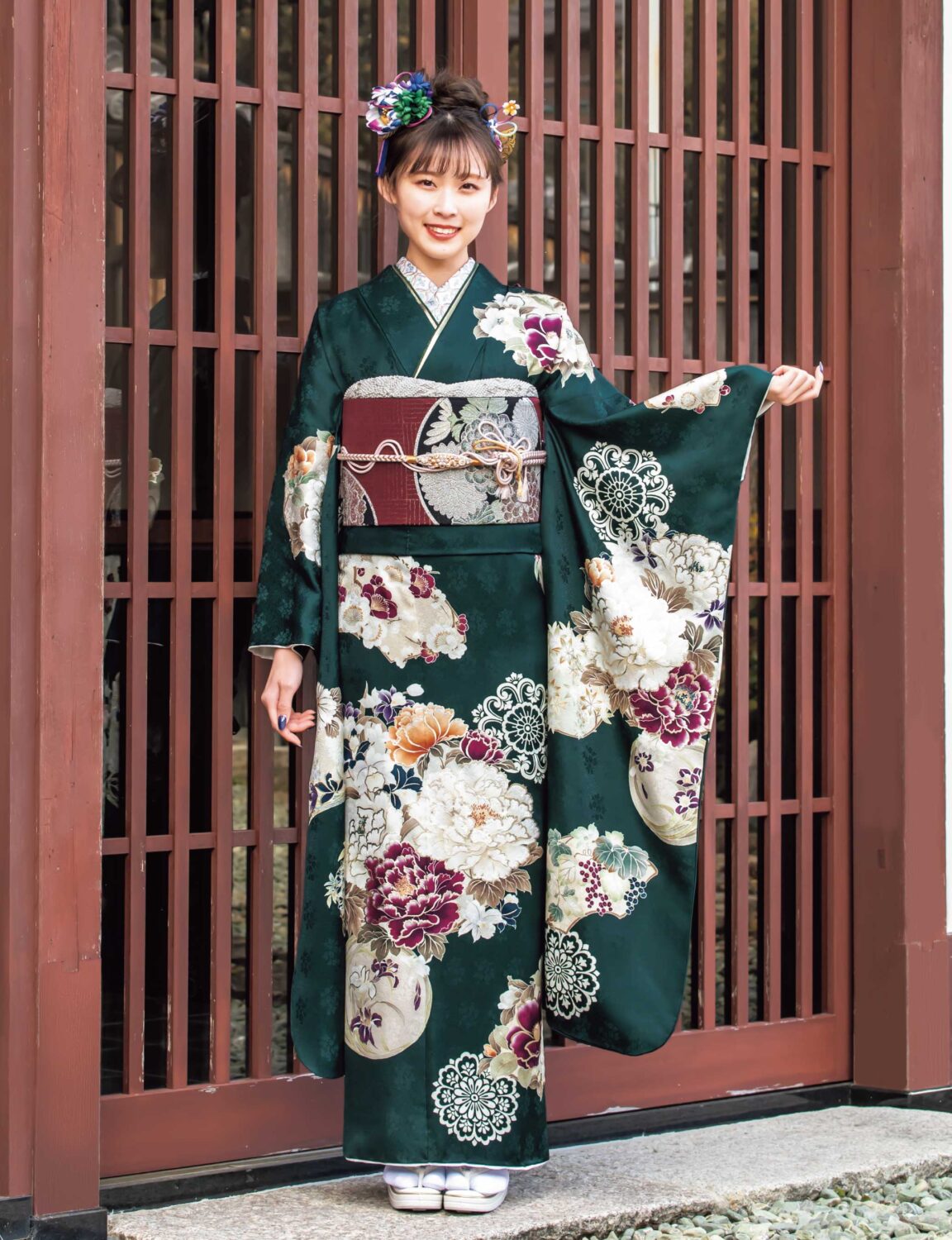 深緑の振袖に牡丹と菊が描かれた華やかな装いの女性