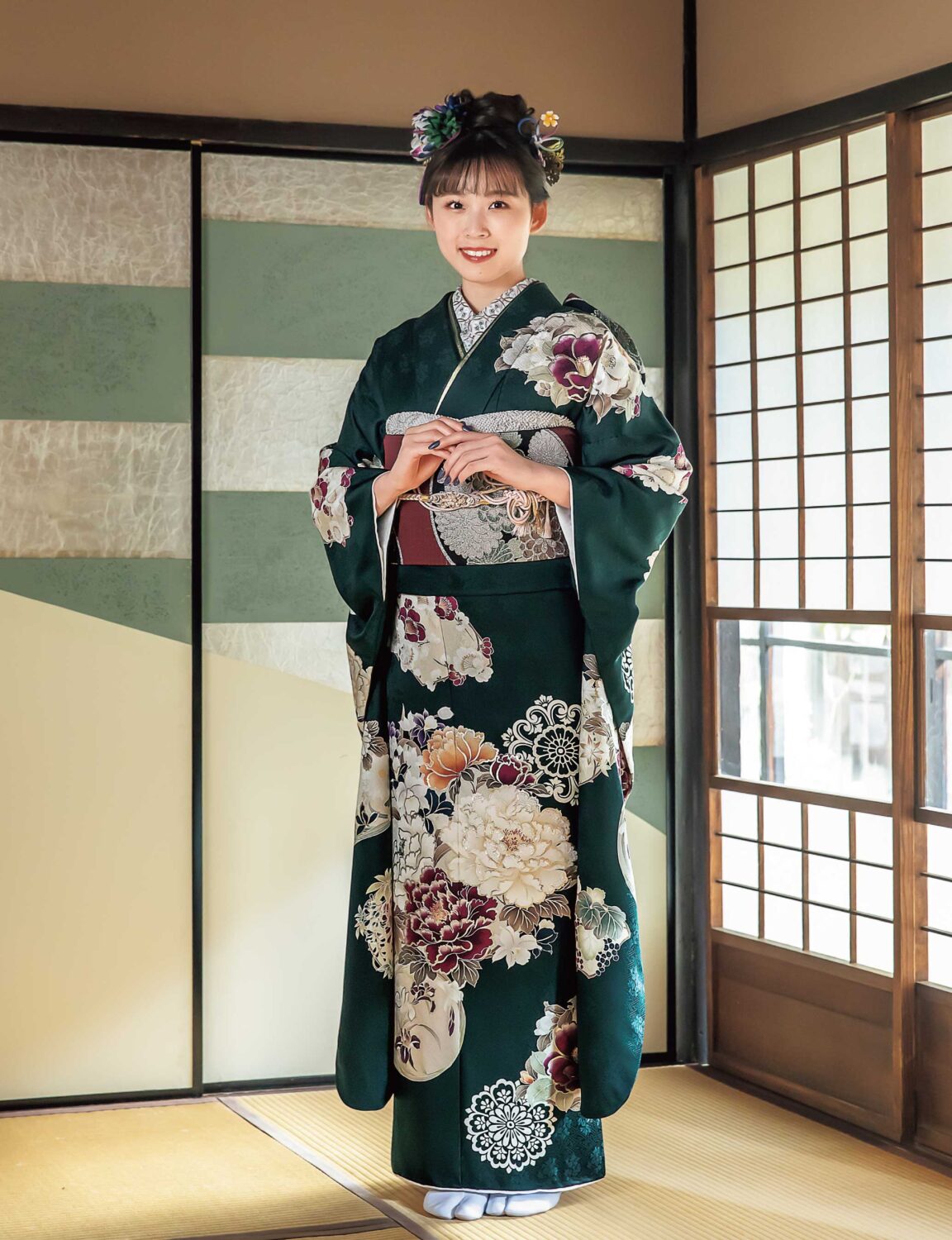 深緑の振袖に牡丹と菊が描かれた華やかな装いの女性