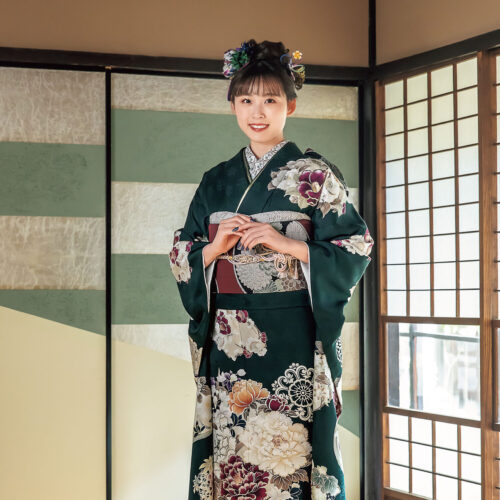 深緑の振袖に牡丹と菊が描かれた華やかな装いの女性