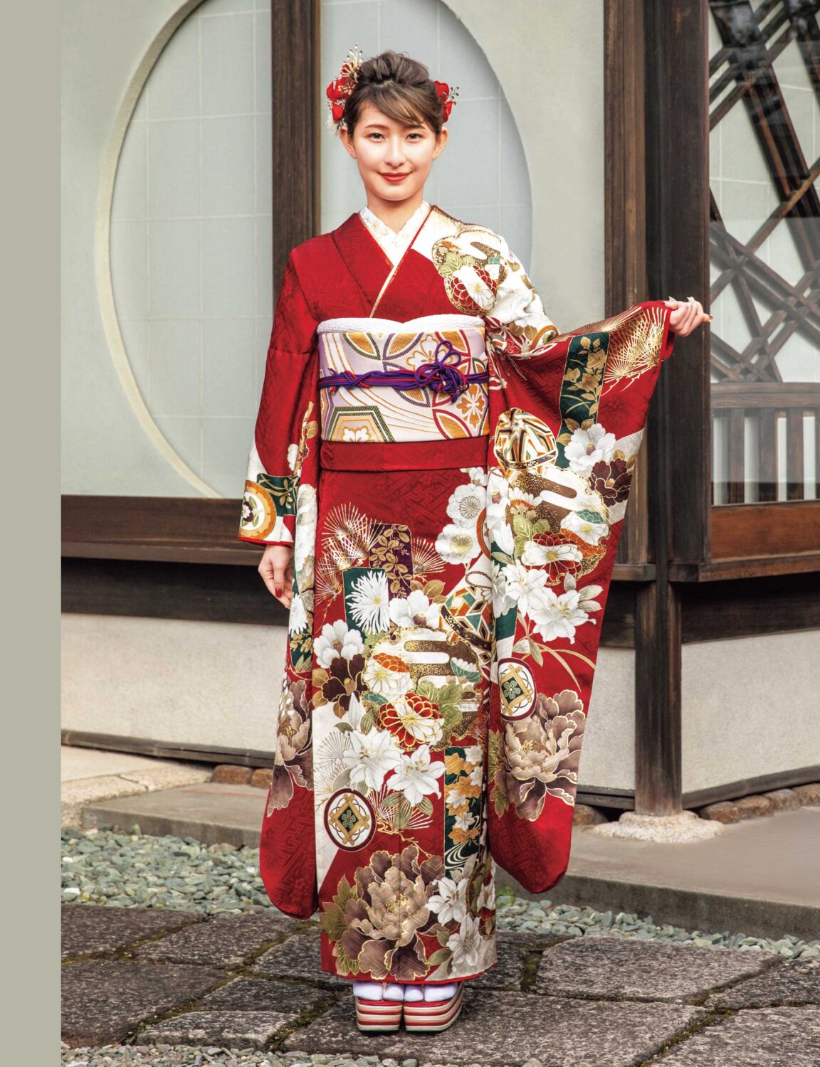 赤地に金彩と花柄が映える振袖姿。帯締と髪飾りが華やかさを添える。