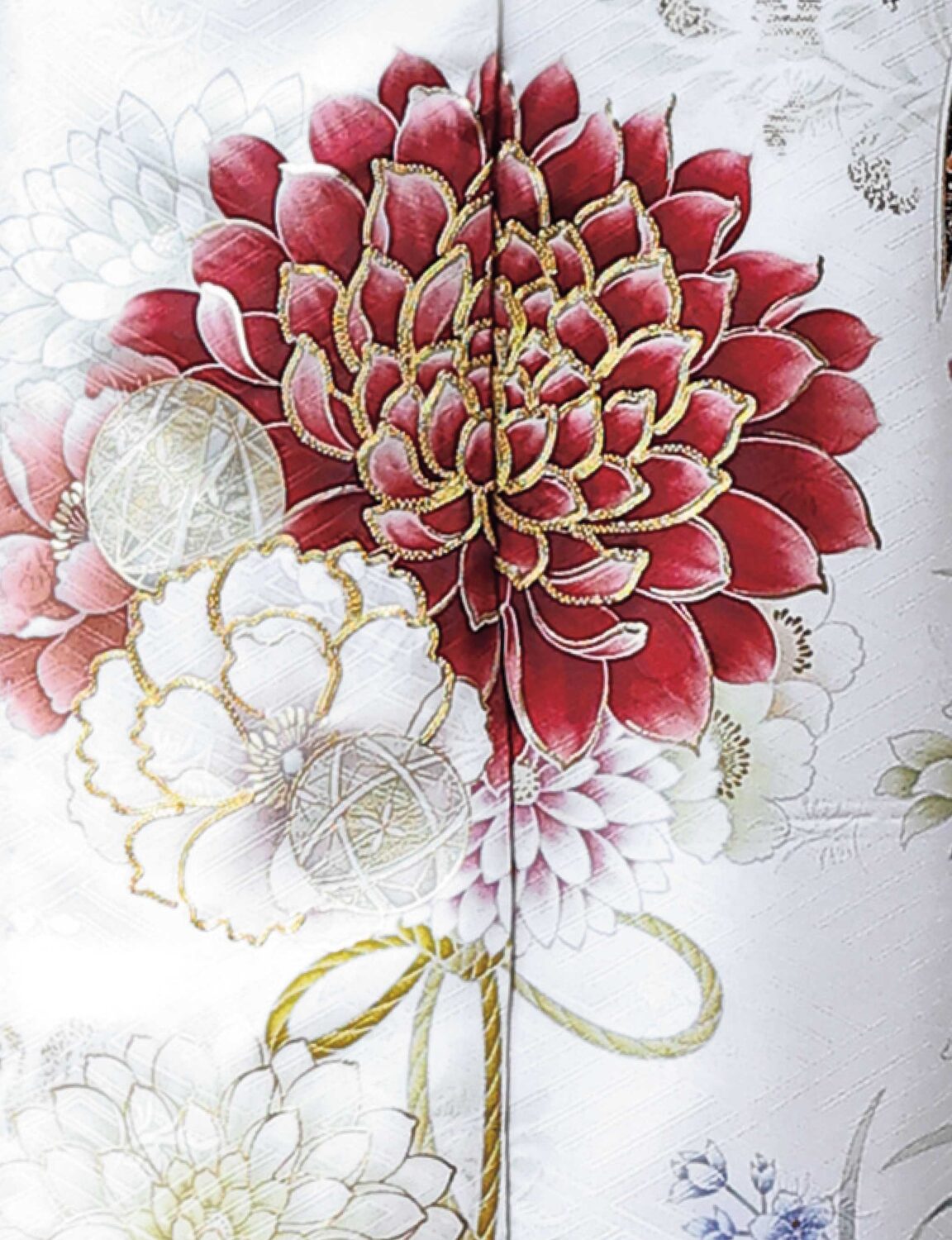 白地に赤・緑・金の菊模様が施された振袖姿の女性。帯締がアクセントになった華やかな装い。