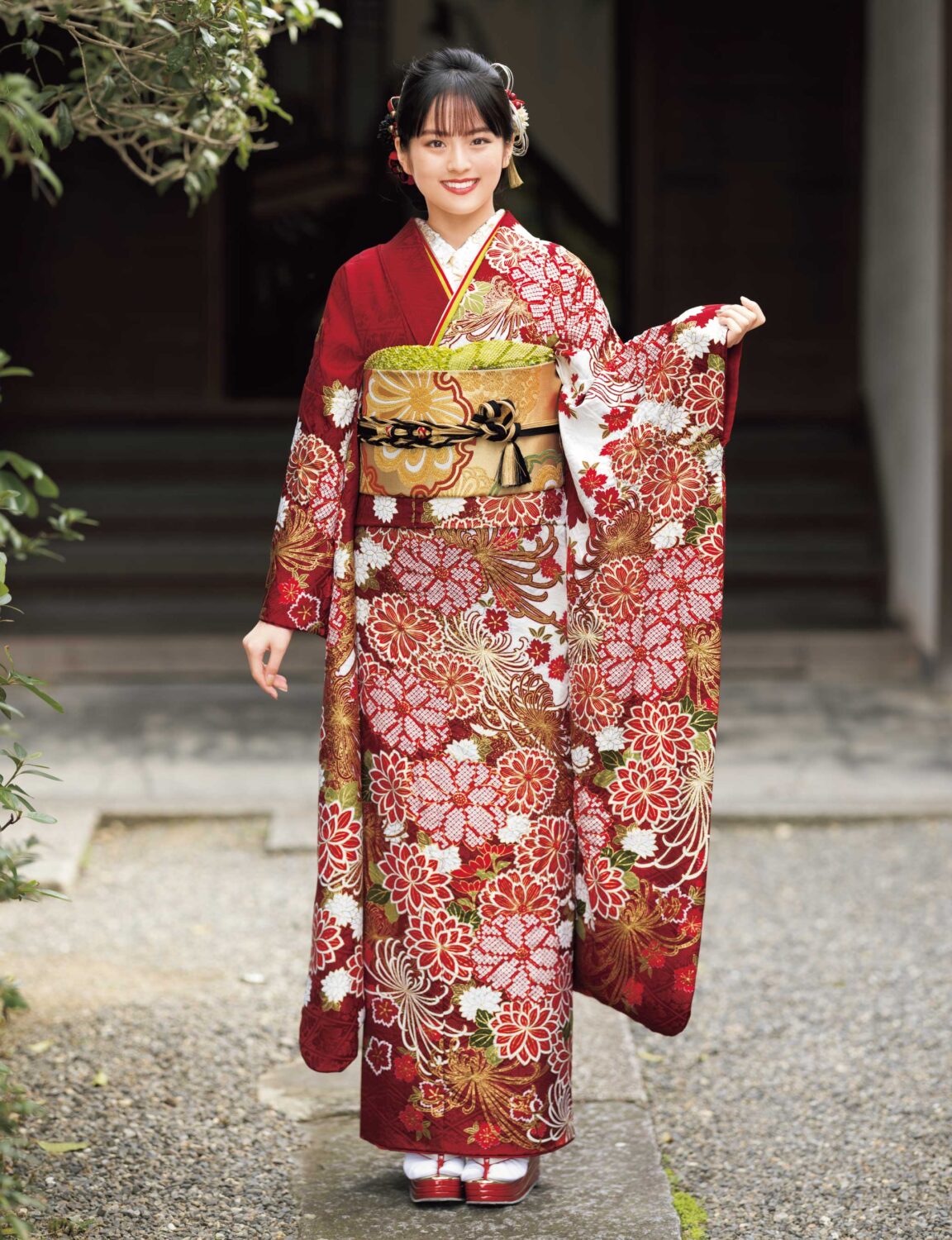 黒地に赤と金の菊模様が施された振袖姿の女性。金の帯締がアクセント。