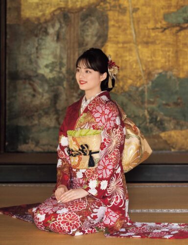 黒地に赤と金の菊模様が施された振袖姿の女性。金の帯締がアクセント。