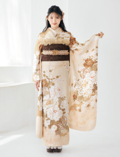 淡いクリーム色に金彩の古典柄が施された振袖を着た女性が、袖を広げて上品なコーディネートを見せている様子。