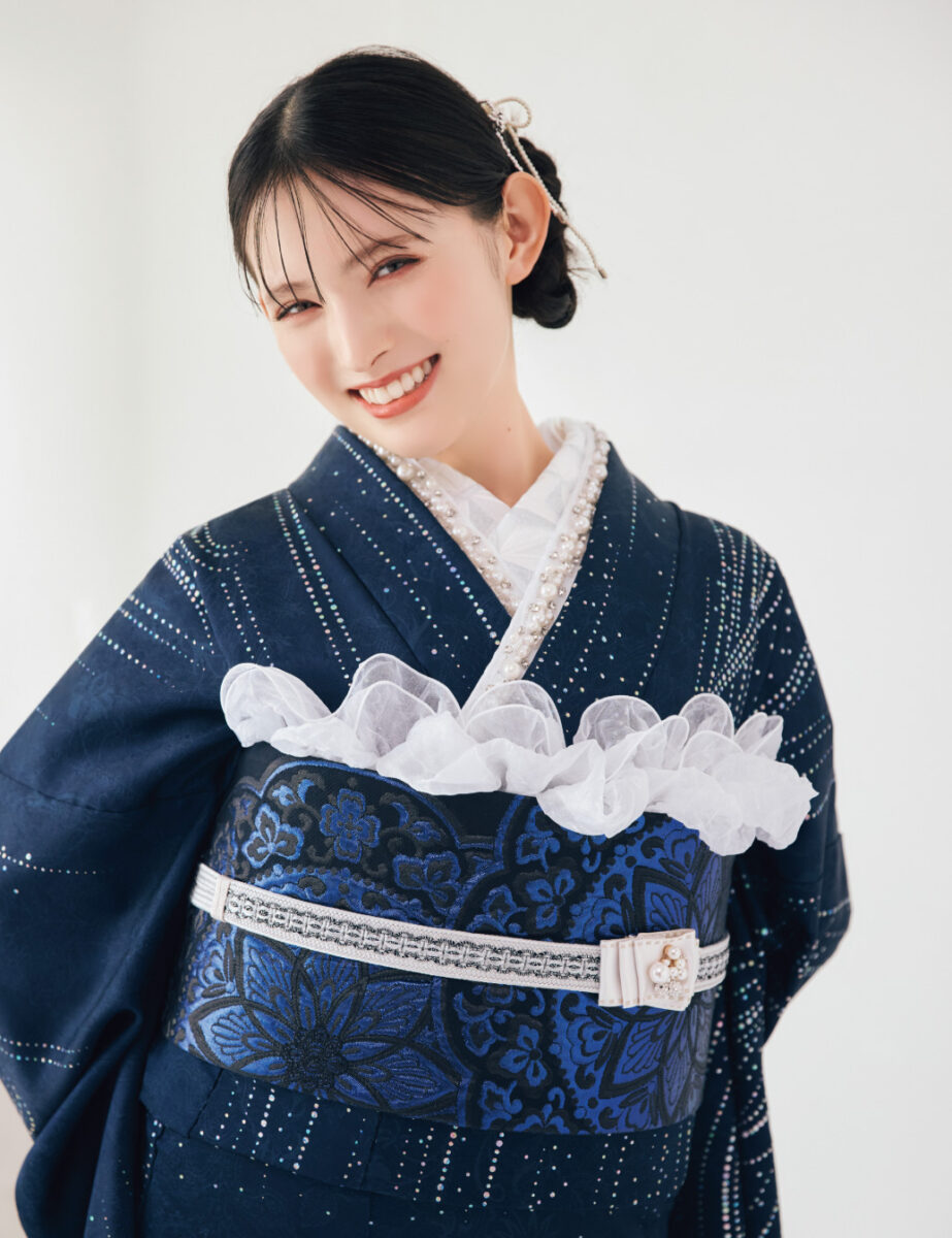 紺地に銀の流線柄が施された振袖を着た女性が、袖を広げて上品なコーディネートを見せている様子。
