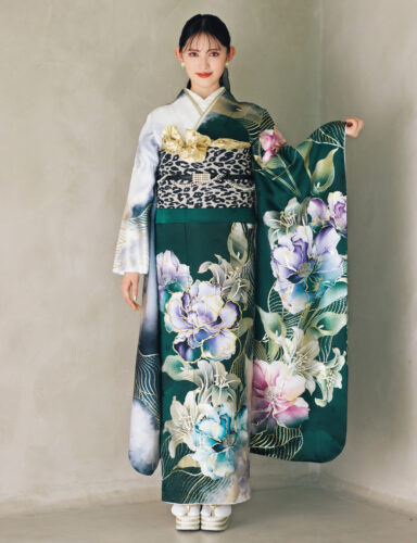 深緑の振袖に大柄の花文様をあしらい、レオパード柄の帯と金の帯締を合わせた女性が、華やかで個性的なコーディネートを見せている様子。