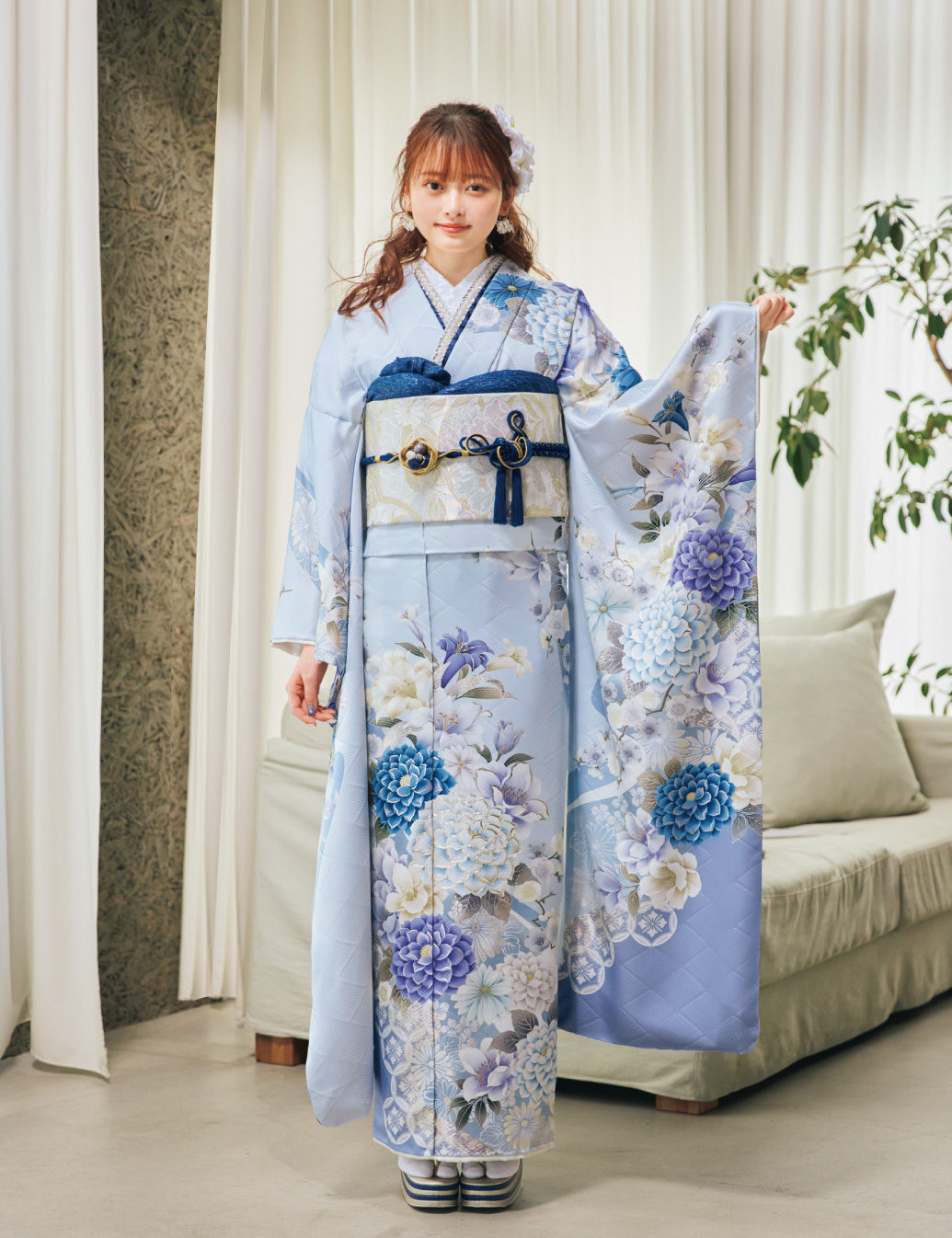 淡い水色の振袖に青・白・薄紫の花柄をあしらい、淡色の帯と紺の帯締を合わせた女性が、爽やかで上品な振袖姿を見せている様子。