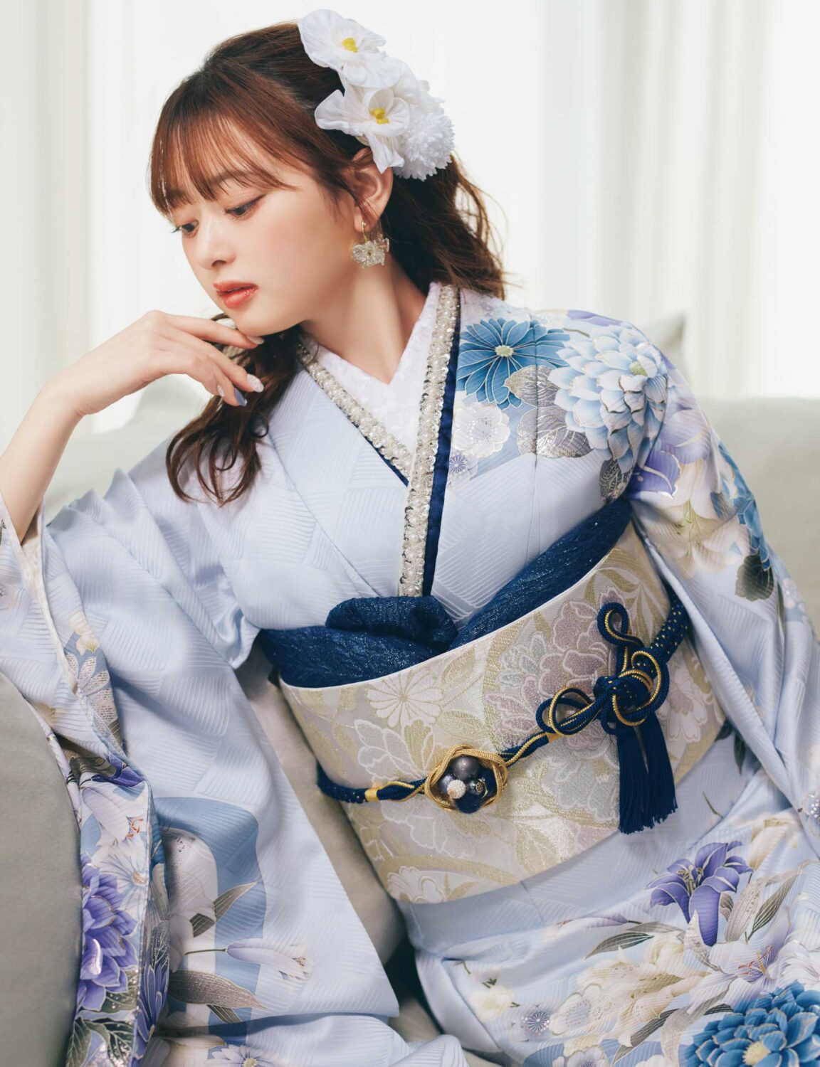 淡い水色の振袖に青・白・薄紫の花柄をあしらい、淡色の帯と紺の帯締を合わせた女性が、爽やかで上品な振袖姿を見せている様子。