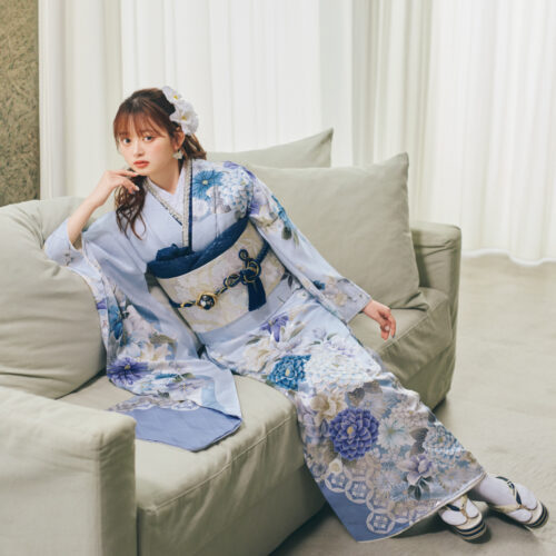 淡い水色の振袖に青・白・薄紫の花柄をあしらい、淡色の帯と紺の帯締を合わせた女性が、爽やかで上品な振袖姿を見せている様子。