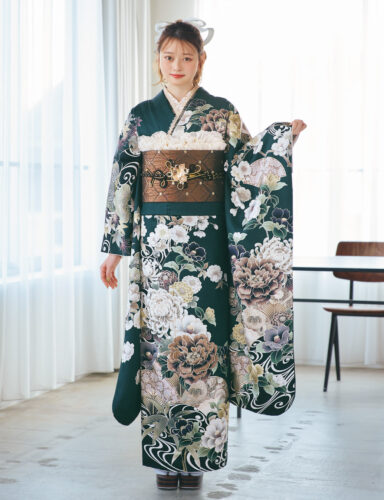 深緑の振袖に白・ベージュ・淡紫の花柄をあしらい、茶系の帯と金黒の帯締を合わせた女性が、上品で華やかな振袖姿を見せている様子。