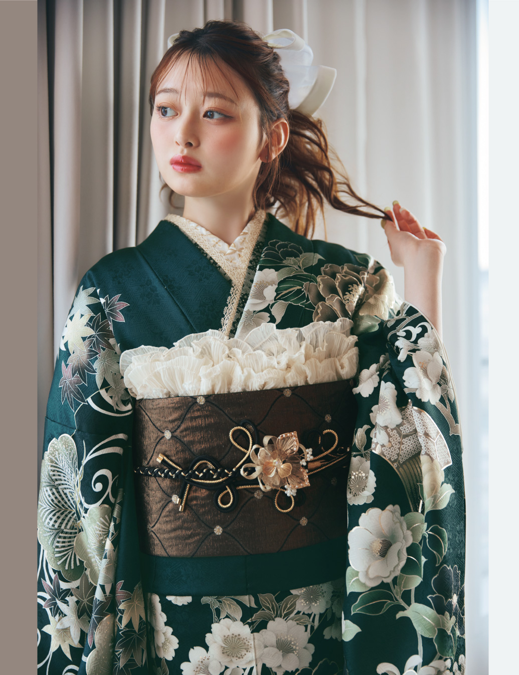 深緑の振袖に白・ベージュ・淡紫の花柄をあしらい、茶系の帯と金黒の帯締を合わせた女性が、上品で華やかな振袖姿を見せている様子。