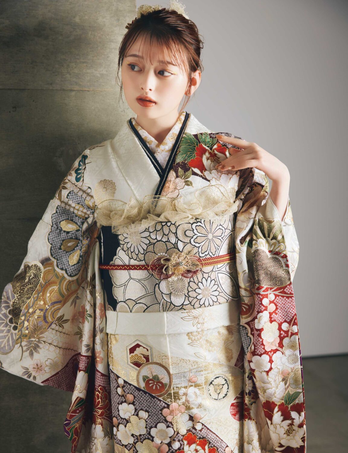 白・金・赤・黒の花柄をあしらった振袖に、黒帯と白の帯締を合わせた女性が、重厚で華やかな振袖姿を見せている様子。