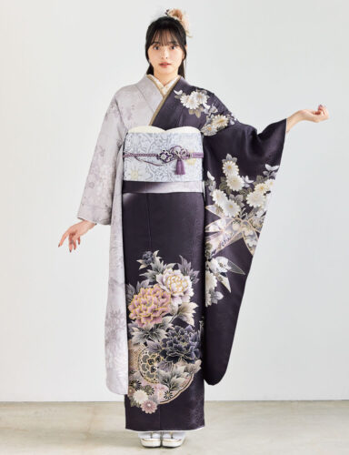 灰紫のグラデーション振袖に白・金・桃・紫の花柄をあしらい、淡灰の帯と紫の帯締を合わせた女性が、上品で華やかな振袖姿を見せている様子。
