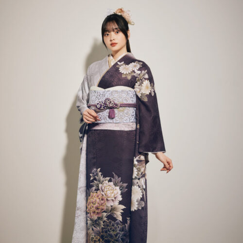 灰紫のグラデーション振袖に白・金・桃・紫の花柄をあしらい、淡灰の帯と紫の帯締を合わせた女性が、上品で華やかな振袖姿を見せている様子。