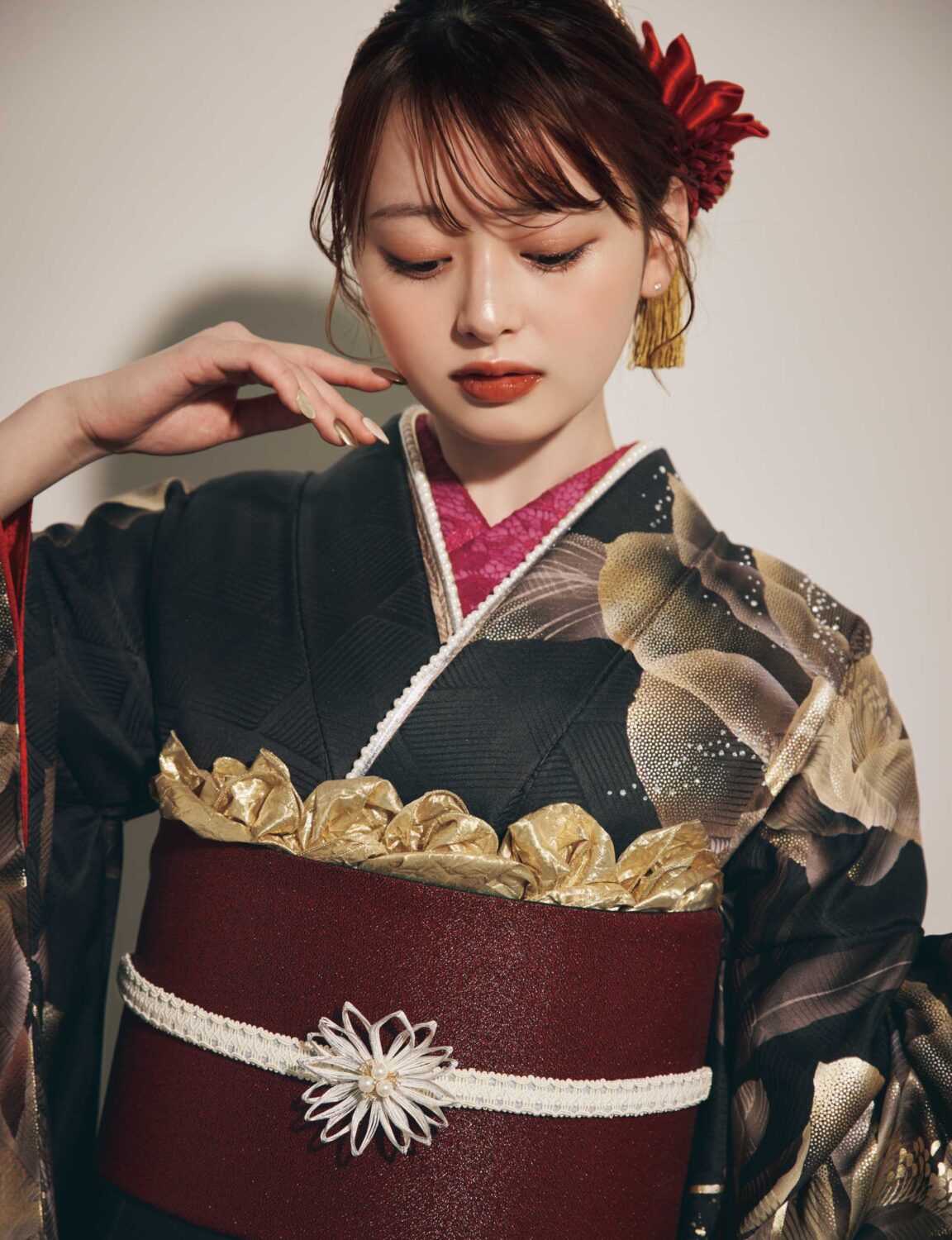 黒地に金・白・赤の花柄をあしらい、深紅の帯と白の帯締を合わせた女性が、重厚で華やかな振袖姿を見せている様子。