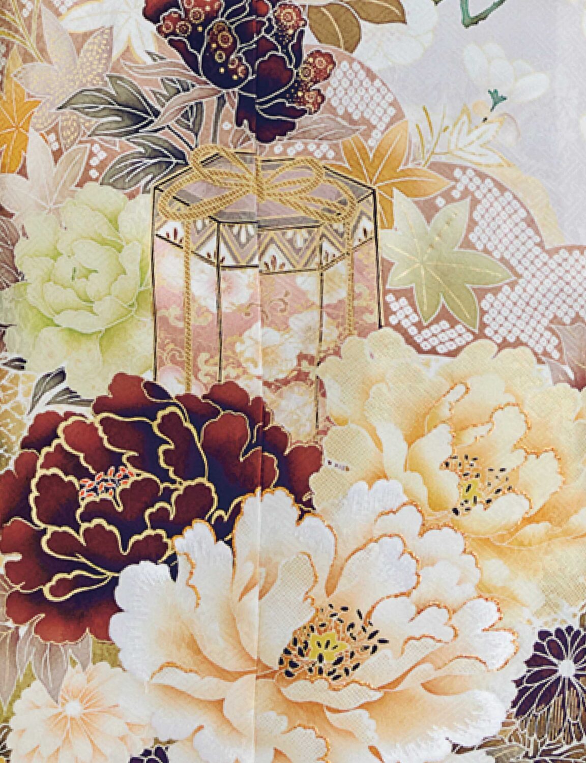 金・クリーム・白・紺・緑の花柄をあしらった振袖に、淡金の帯と青の帯締を合わせた女性が、重厚で上品な振袖姿を見せている様子。