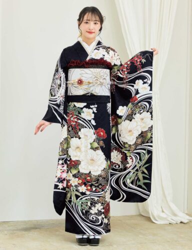 黒地の振袖に白・赤・緑・金の花柄をあしらい、淡色の帯を合わせた女性が、重厚で華やかな振袖姿を見せている様子。